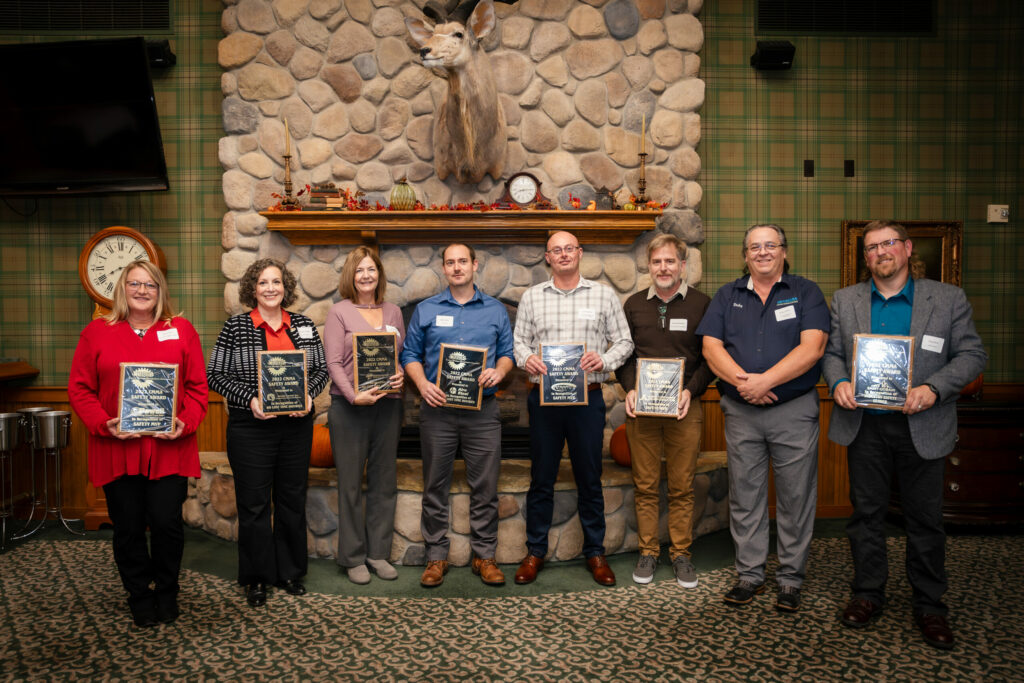 Group holding awards in rustic room.