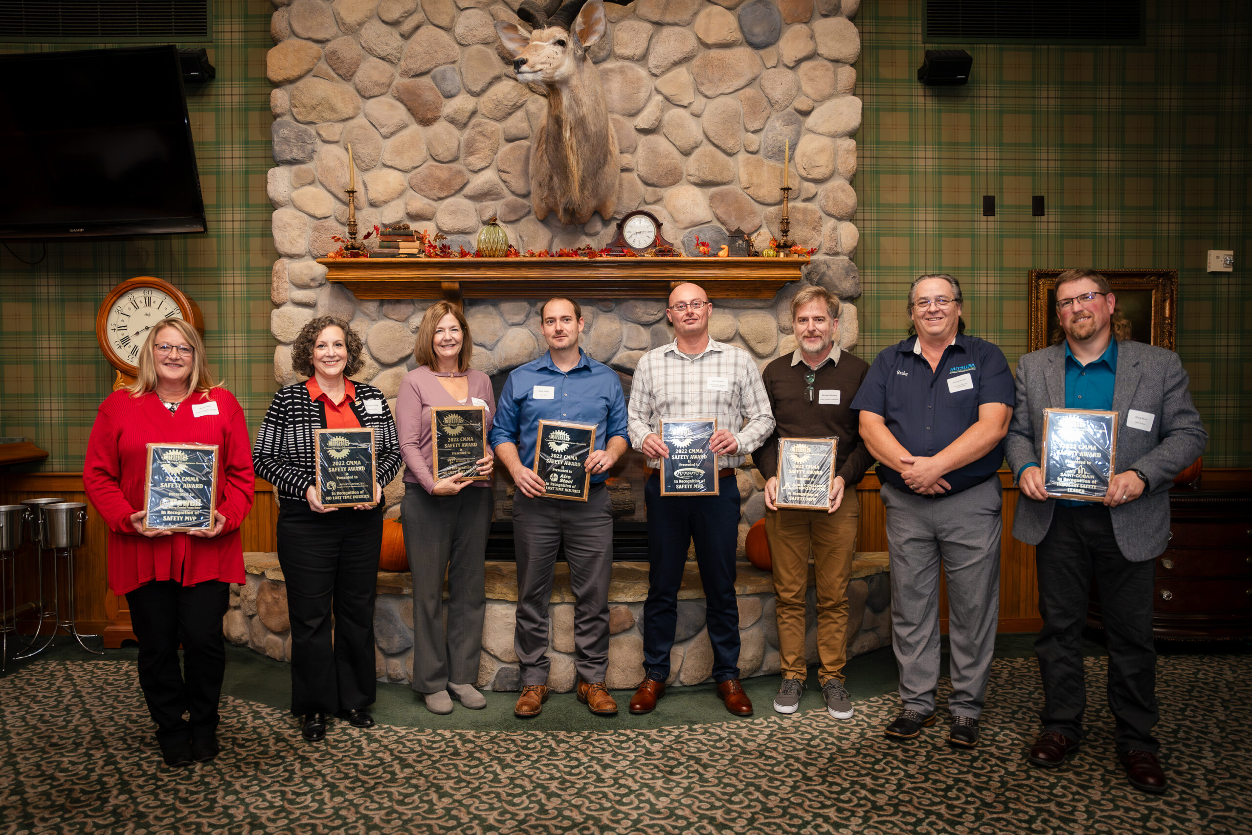 Group holding awards in rustic room.