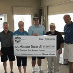 Group holding large donation check indoors.