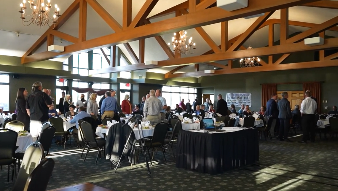 Business conference attendees mingling in large banquet room.