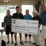 Group holding large ceremonial check indoors.