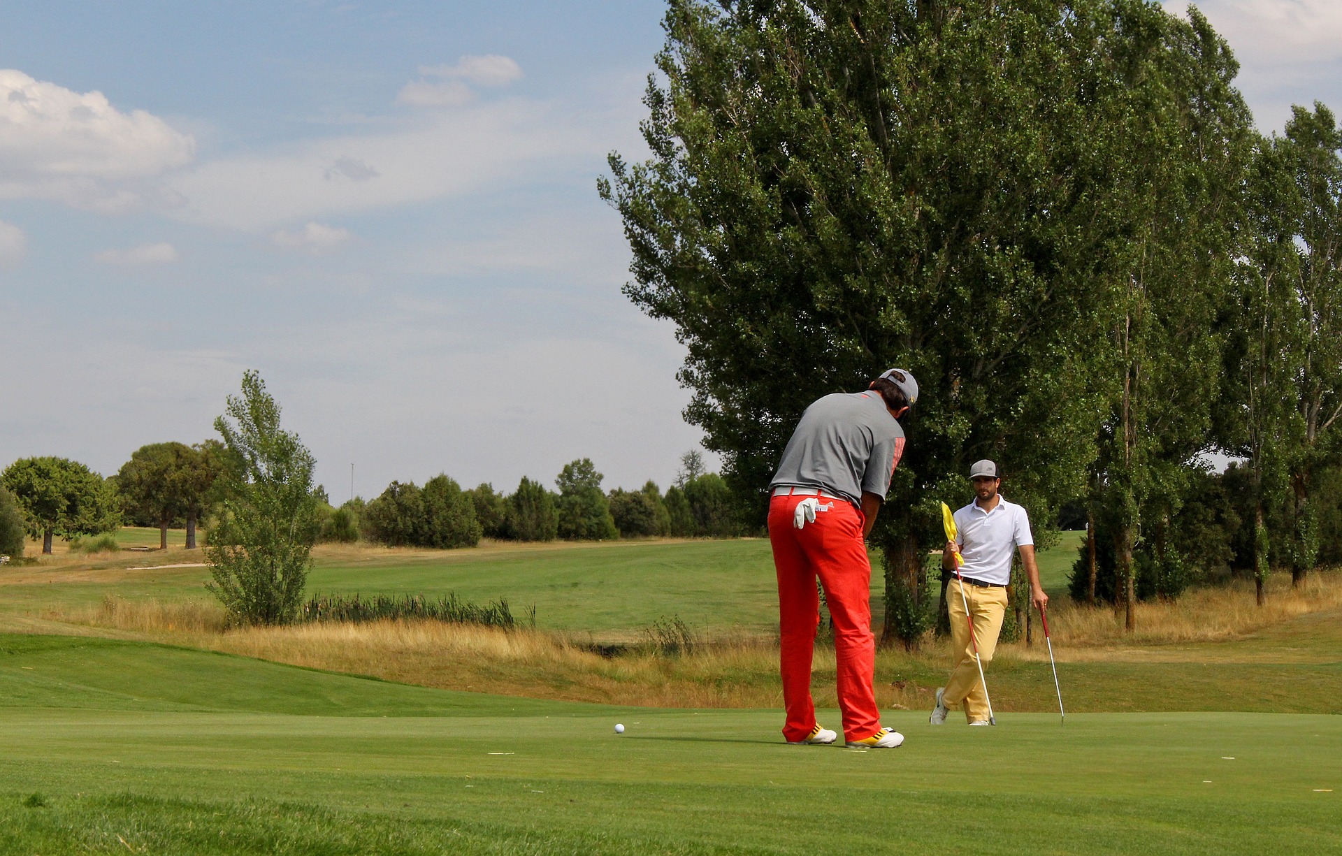 Golfers on green, one preparing to putt