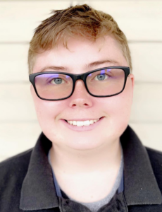 Person smiling with glasses and short hair