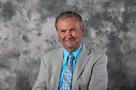 Man in gray suit with blue shirt smiling