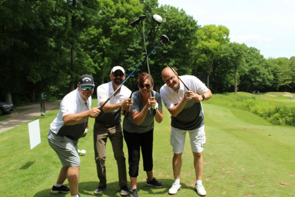 Group posing with golf clubs on course