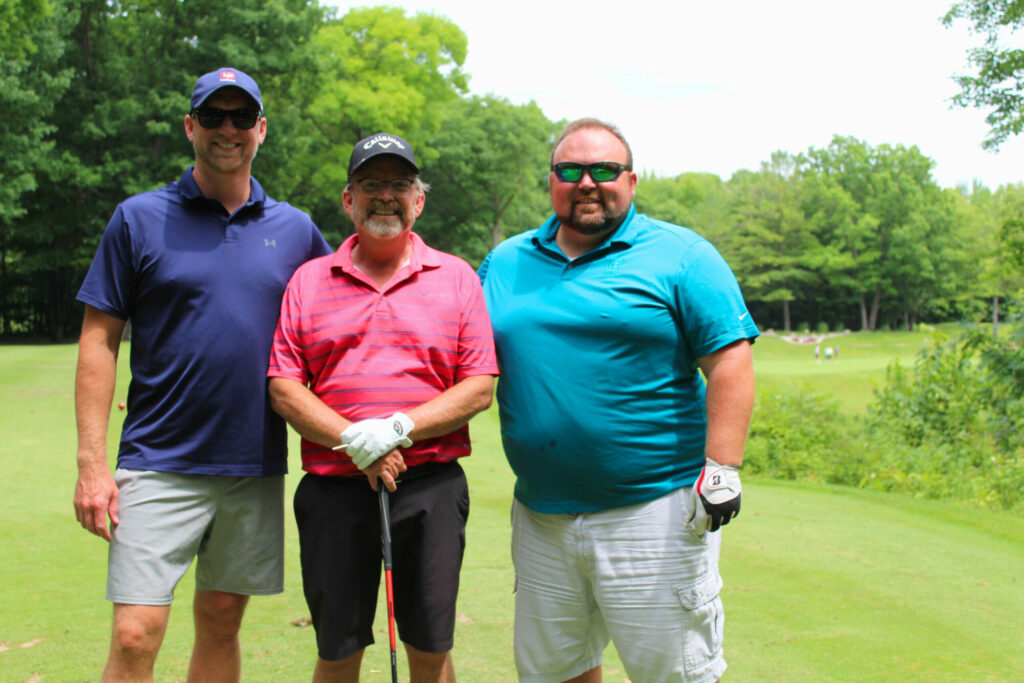 Three men posing on golf course