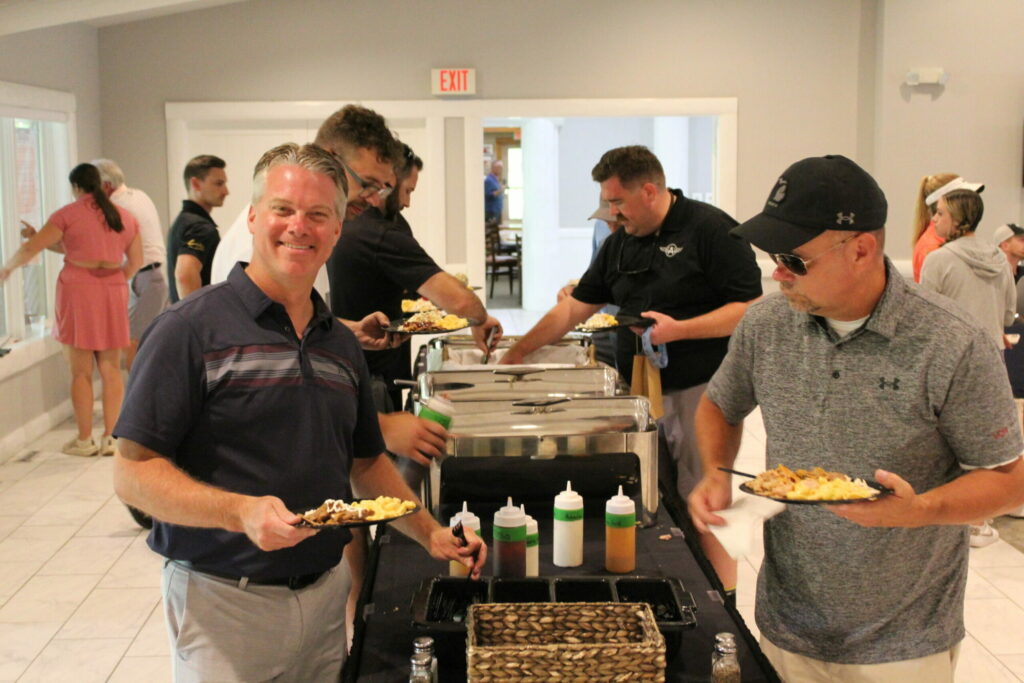 People serving food at buffet table indoors.