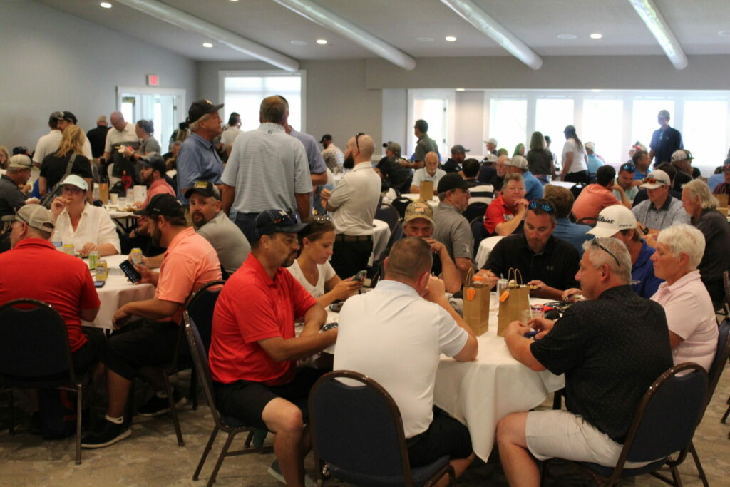 Large group gathers at tables for a social event.