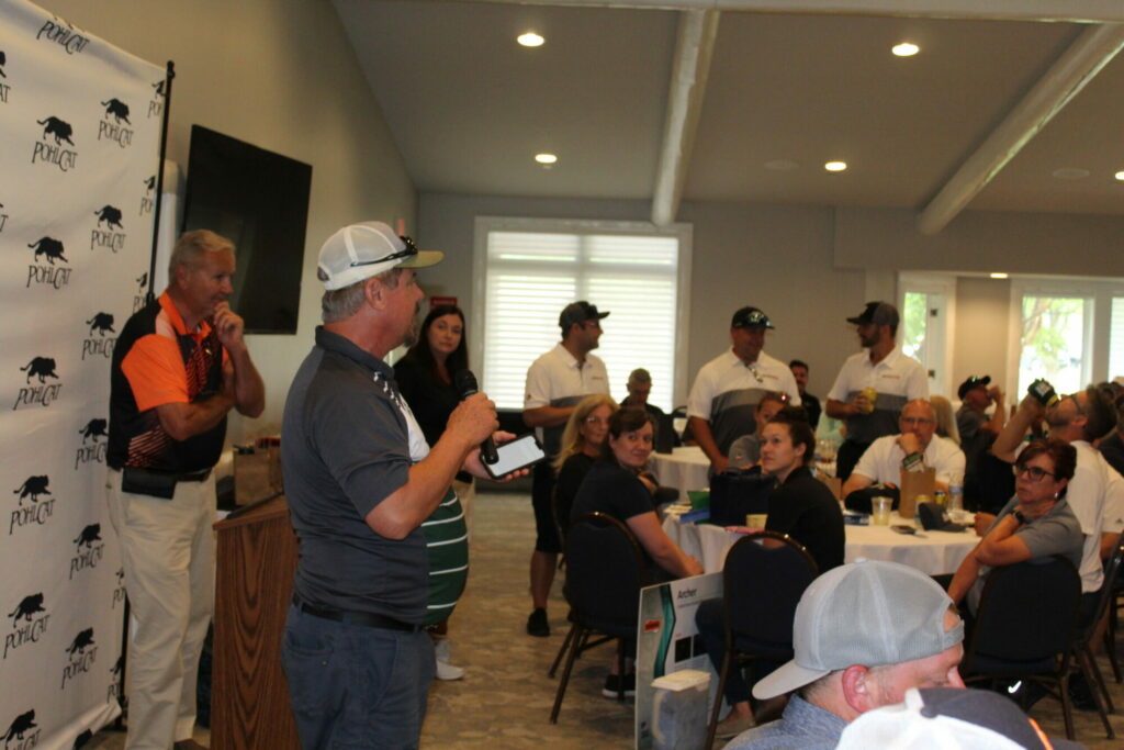 Man speaks at indoor event with seated audience.