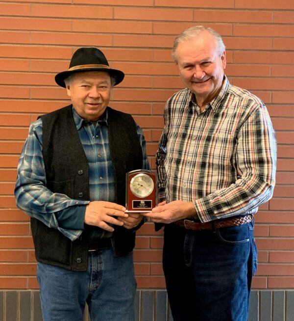 Two men holding a clock plaque together, smiling.