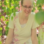 Smiling person sitting among green leaves