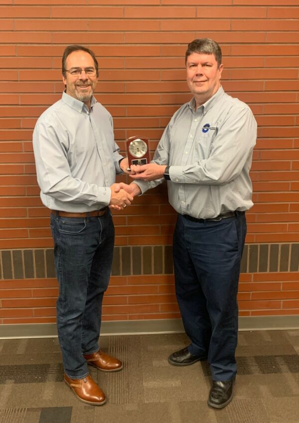 Two men shaking hands with an award