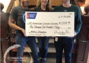 Three people holding large donation check for charity.