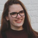 Person smiling in front of brick wall