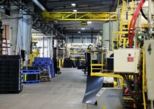 Industrial warehouse with machinery and stacked pallets.