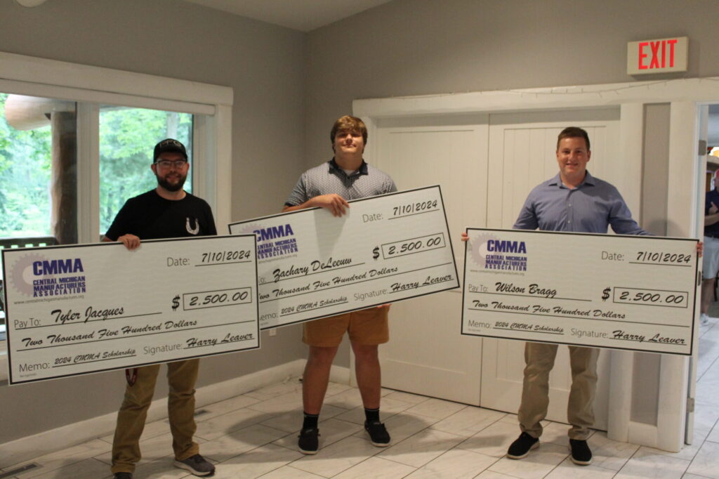 Three men holding large scholarship checks indoors.