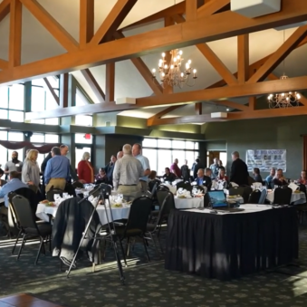 Business conference attendees mingling in large banquet room.