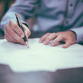 Person writing on documents with pen