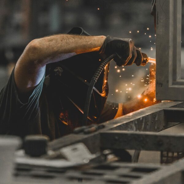 Welder working with sparks flying in workshop.